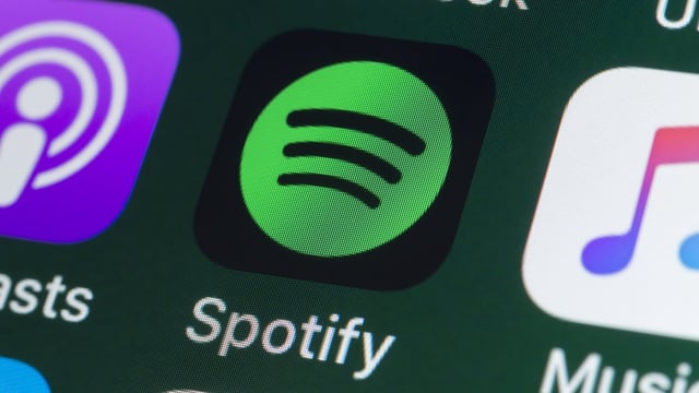 he buttons of the music streaming app Spotify, surrounded by Podcasts, Apple Music, Facebook and other apps on the screen of an iPhone.