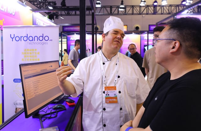 A Yordando Technologies staff member discusses the firm’s artificial intelligence-powered kitchen application to visitors during the 2024 World AI Conference in Shanghai on July 6, 2024. Photo: Xinhua
