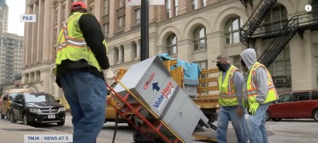 Milwaukee city workers move an absentee ballot drop box