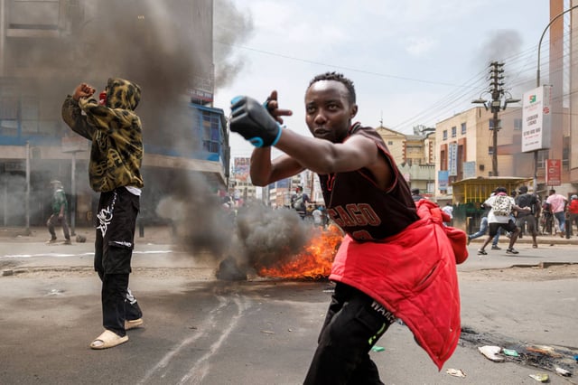 Protesters gesture at Kenya's anti-riot police around a burning barricade during an anti-government protest. Photo: AFP