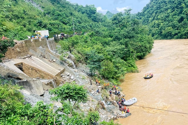 Rescuers search for survivors in the river Trishuli in Simaltar after a landslide triggered by heavy rains swept two buses off a highway