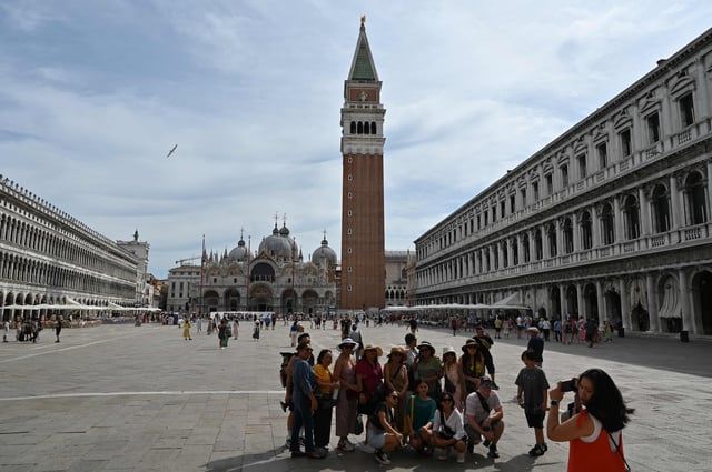 A view taken on July 31, 2023 shows tourists taking a souvenir group photo at St. Mark's square in Venice. Unesco is recommending that Venice be placed on the list of World Heritage in Danger, due to mass tourism and climate change.