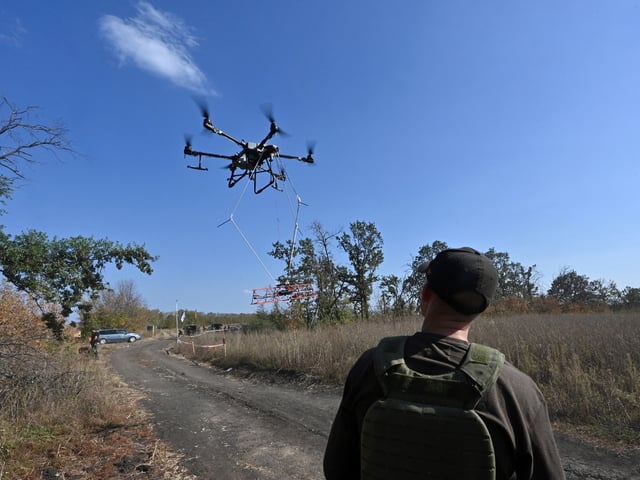 An operator of the volunteer organization 'Postup' controls the flight of an UAV carrying a metal detector to search for mines near the town of Derhachi, Kharkiv region, on October 1, 2023. (Photo by SERGEY BOBOK / AFP) (Photo by SERGEY BOBOK/AFP via Getty Images)