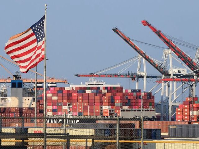 A US flag flies near containers stacked high on a cargo ship at the Port of Los  Angeles on September 28, 2021 in Los Angeles, California. A record number of cargo ships are stuck floating and waiting off the southern California coast amid a supply chain crisis which could mean fewer gifts and toys for Christmas this year as a combination of growing volumes of cargo, Covid-19 related saftey measures and a labor shortage slow the handling and processing of cargo from each ship. (Photo by Frederic J. BROWN / AFP) (Photo by FREDERIC J. BROWN/AFP via Getty Images)