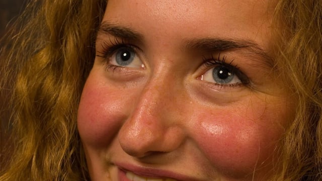 Young girl with blonde hair smiles while blushing