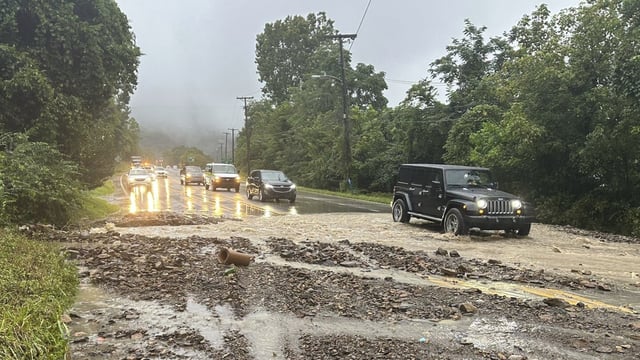 Vehicles maneuver around a mudslide caused by heavy rains along U.S. Route 60 on Monday, Aug. 28, 2023, in Cedar Grove, W.V. (Ava Rash/WCHS-TV via AP)