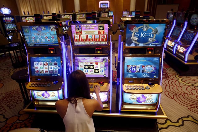 A casino trainee demonstrates how to play a slot machine in the Philippines, April 16, 2015.