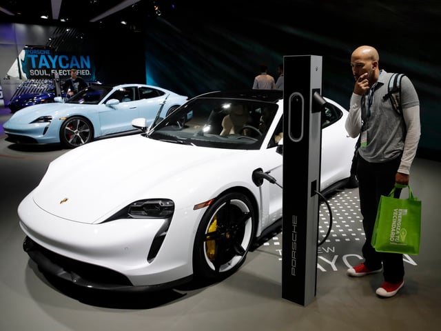 The Porsche Taycan Turbo, in white, and 4s, in blue, electric vehicles are shown at the AutoMobility LA auto show Thursday, Nov. 21, 2019, in Los Angeles. (AP Photo/Marcio Jose Sanchez)