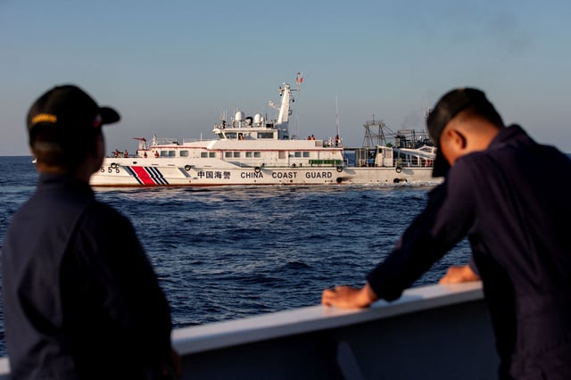 FILE PHOTO: Members of the Philippine Coast Guard stand alert as a Chinese Coast Guard vessel blocks their way to a resupply mission at Second Thomas Shoal in the South China Sea, March 5, 2024. REUTERS/Adrian Portugal/File Photo