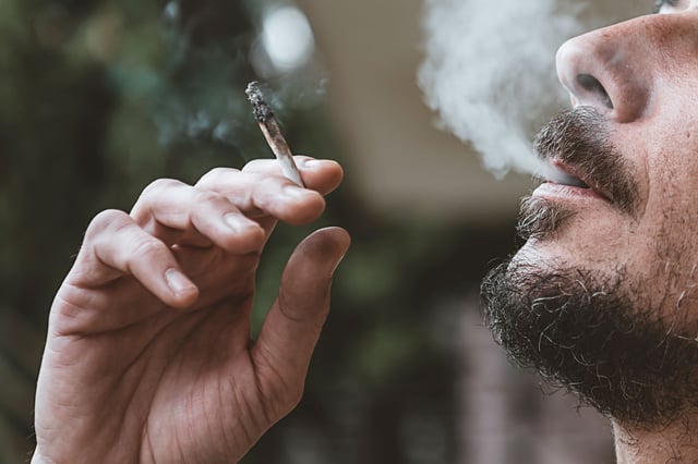 Bearded man smoking a marijuana joint