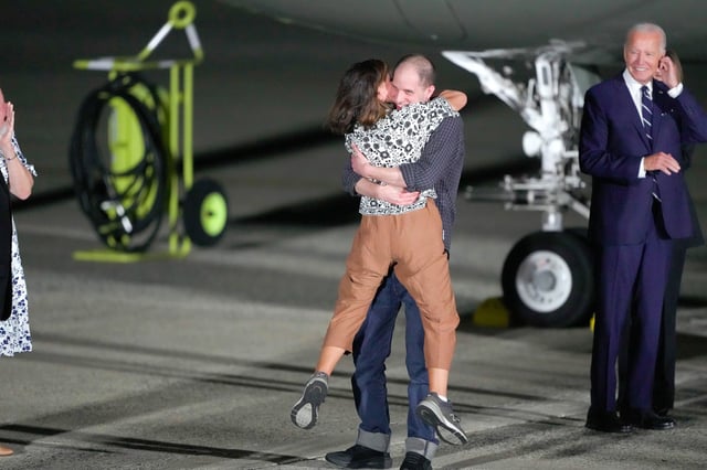 Reporter Evan Gershkovich hugs his mother, Ella Milman, as President Joe Biden, right, looks on at Andrews Air Force Base, Md., on Aug. 1, 2024.