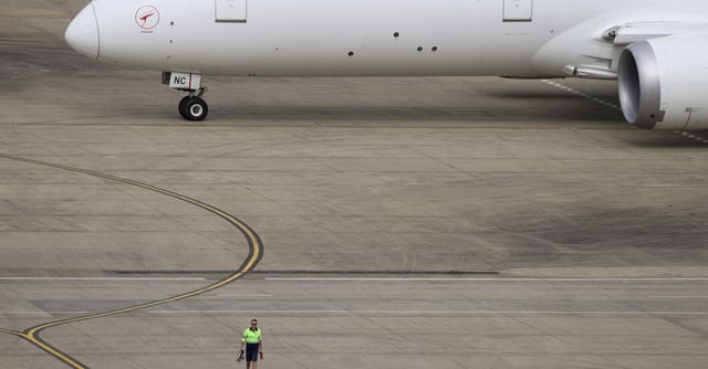 A ground worker walking near a Qantas plane is seen from the international terminal at Sydney Airport in Australia, November 29, 2021.  REUTERS/Loren Elliott/file photo/File Photo
