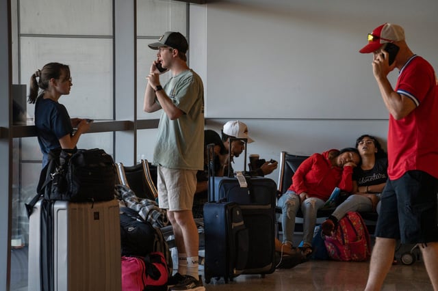 John Box (right) talks on the phone while waiting for his Delta flight in Terminal 3, July 19, 2024, at Sky Harbor International Airport in Phoenix, Ariz. On Monday, Austin-based cybersecurity company CrowdStrike was sued by passengers affected by a massive tech outage that snarled transportation systems around the globe.