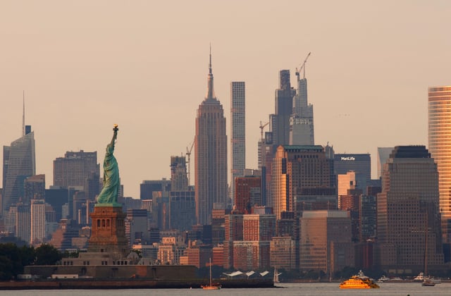 The sun sets on the Empire State Building and the Statue of Liberty in New York City seen from Bayonne, New Jersey on July 26