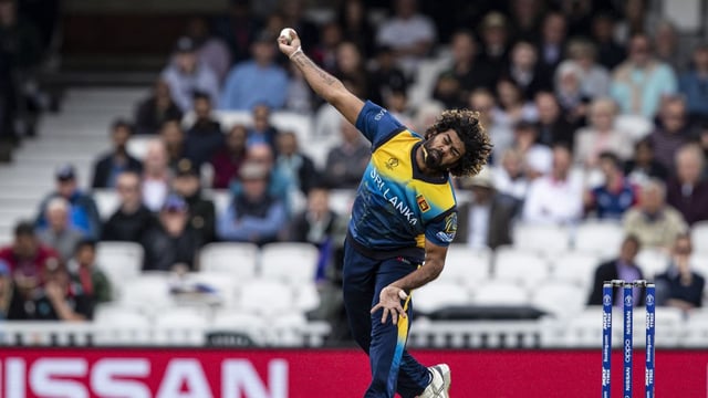 bowler bowling with outstretched arm in stadium