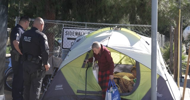 Police remove an unhoused woman from her tent