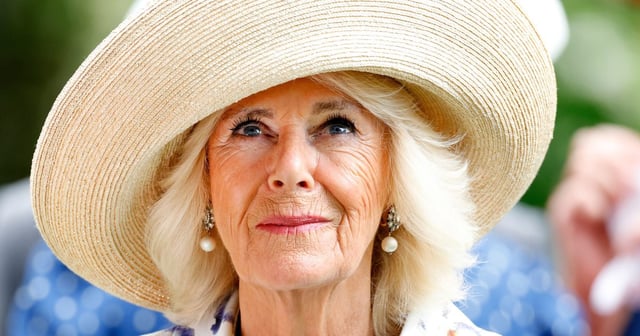 Queen Camilla, wearing a hat and looking up