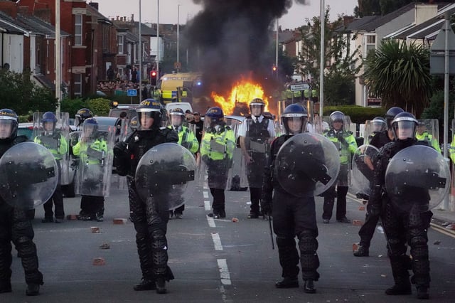 Riot police hold back protesters after disorder broke out on July 30, 2024, in Southport, England. Rumours about the identity of the 17-year-old suspect in yesterday's deadly stabbing attack here have sparked a violent protest. According to authorities and media reports, the suspect was born in Cardiff to Rwandan parents, but the person cannot be named due to his age. A false report had circulated online that the suspect was a recent immigrant who crossed the English Channel last week and was "on an MI6 watchlist." (Photo by Christopher Furlong/Getty Images)
