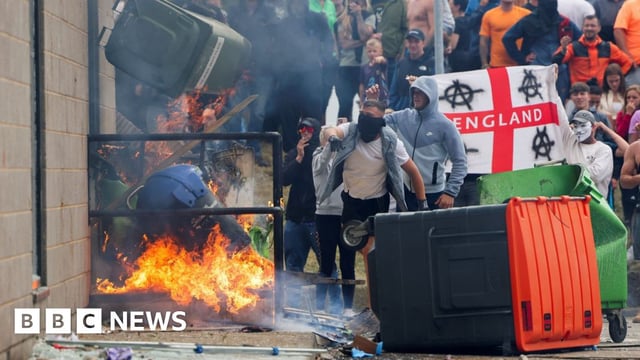 Protestors throw a garbage bin on fire outside a hotel housing asylum seekers in Rotherham, England on 4 August 2024