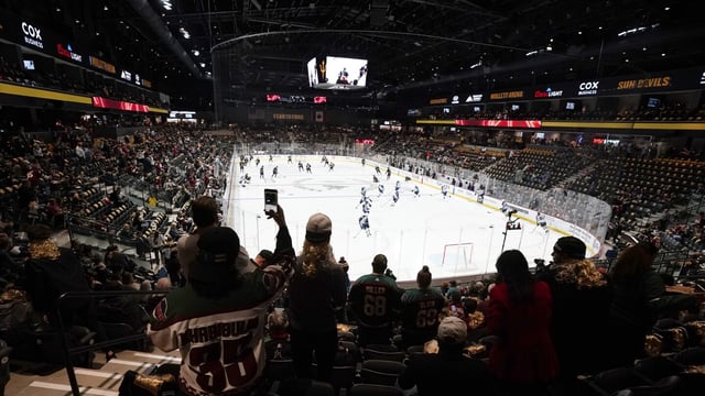 FILE - Fans watch as players warm up prior to the Arizona Coyotes' home-opening NHL hockey game against the Winnipeg Jets at the 5,000-seat Mullett Arena in Tempe, Ariz., Oct. 28, 2022. The Coyotes say owner Alex Meruelo has executed a letter of intent to buy a piece of land for a potential arena in Mesa, Arizona. The move comes months after voters in Tempe rejected a referendum to construct an arena there for the NHL club. (AP Photo/Ross D. Franklin, File)
