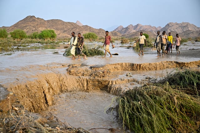 Sudanese people cross a damaged road after the collapse of the Arbaat Dam, 40km north of Port Sudan following heavy rains and torrential floods on August 25, 2024. (Photo by AFP) (Photo by -/AFP via Getty Images)