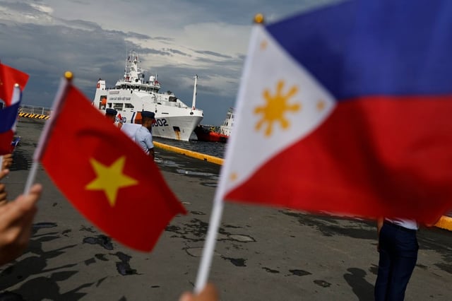 Philippine coastguard personnel wave flags as a Vietnam Coast Guard patrol ship makes a port call at the Port of Manila on August 5. Photo: EPA-EFE