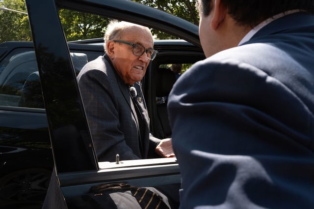 Former New York City Mayor Rudy Giuliani climbs into his vehicle after speaking with people and police outside a designated protest area near the United Center which is hosting the Democratic National Convention on August 20 in Chicago.