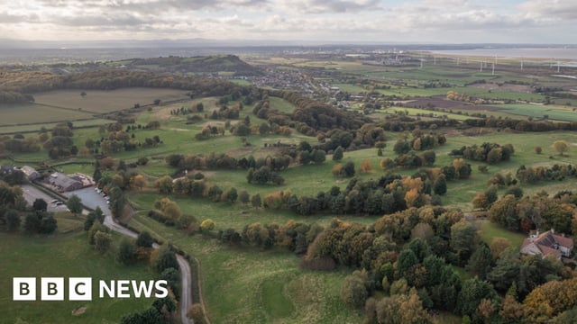 Aerial view of hills interspersed with patches of woodland and fields stretching into the distance.