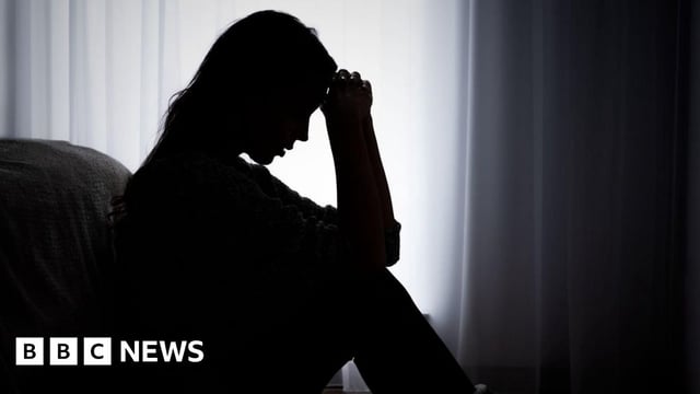Silhouette of an anonymous woman sat looking distressed