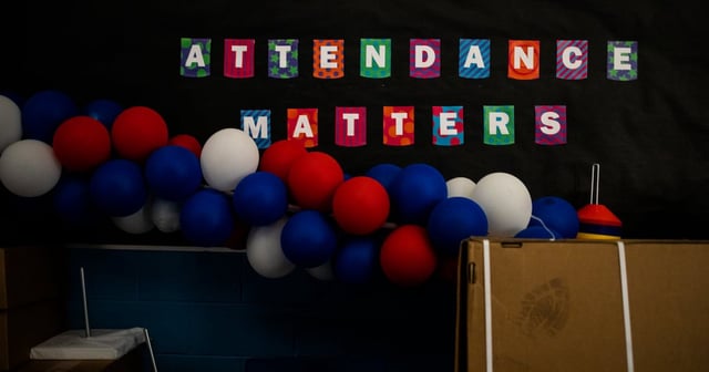 A garland of red, white, and blue balloons hangs in front of a sign that reads “Attendance matters.”