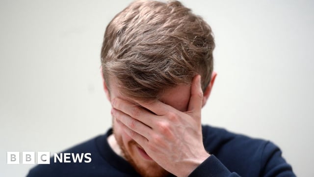 Stock image of a man with his hand on his head - it appears he is in pain - possibly suffering from a headache or migraine